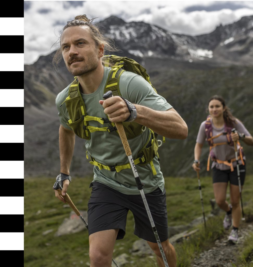 Wanderer mit Funktionsrucksäcken auf einem Bergweg, Outdoor-Ausrüstung zum Trekking, Alpenlandschaft im Hintergrund